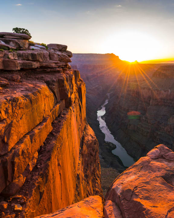 the sun setting over the edge of a canyon