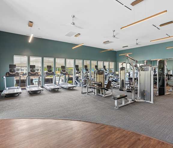 A gym with a variety of equipment including treadmills, weights, and exercise machines.