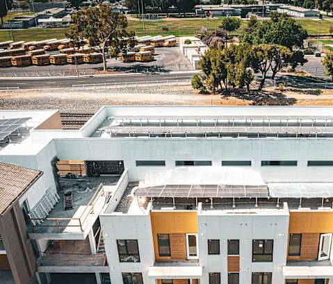 A large white building with a yellow section in the middle is under construction.