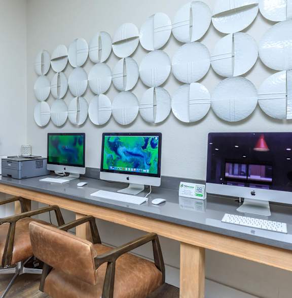 A modern workspace with a wooden desk, three monitors, and a unique wall decoration.