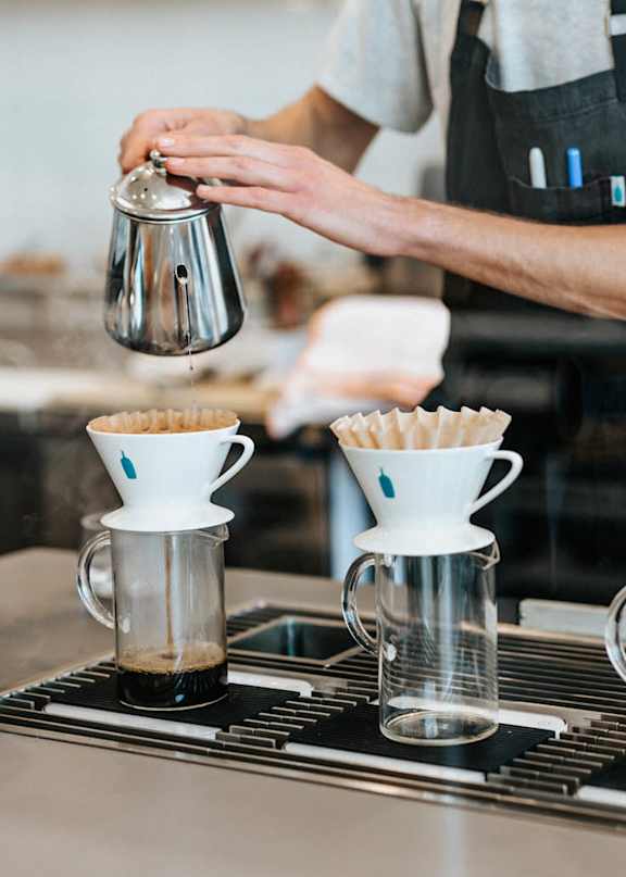 A person is making coffee in a professional setting.