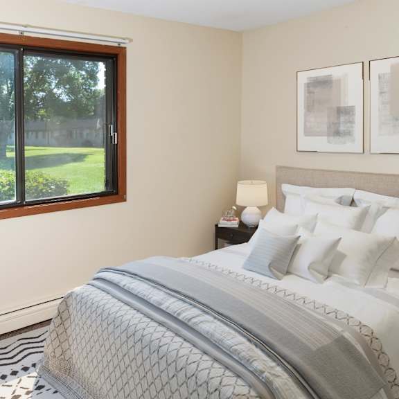 A bedroom with a large bed and a window with a view of a green lawn.