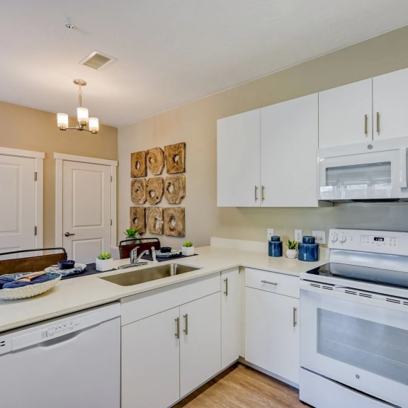 a kitchen with white cabinets and appliances and a sink