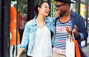 a man and a woman walking down the street with shopping bags
