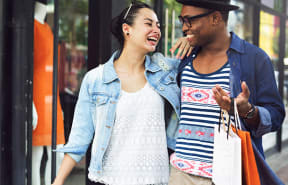 a man and a woman walking down the street with shopping bags