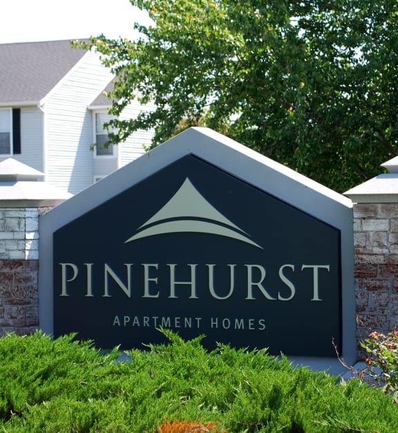 a sign that says pinehurst apartment homes in front of a house