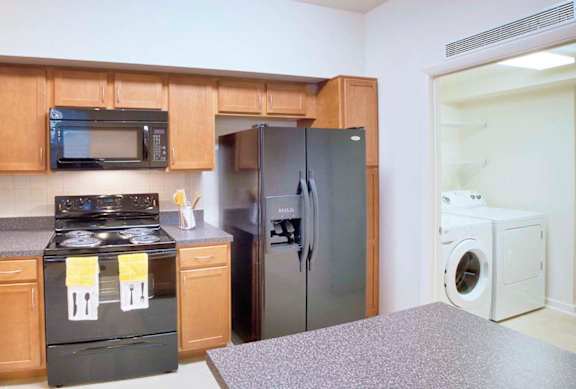 A kitchen with a black stove top oven and a black microwave above it.