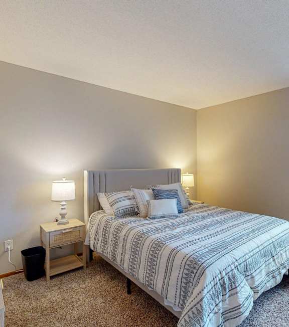 A bedroom with a bed, nightstand, and window.