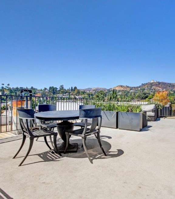 A table and chairs set on a patio with a mountain in the background.