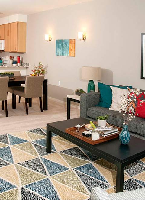 A modern living room with a dining table and a grey couch.