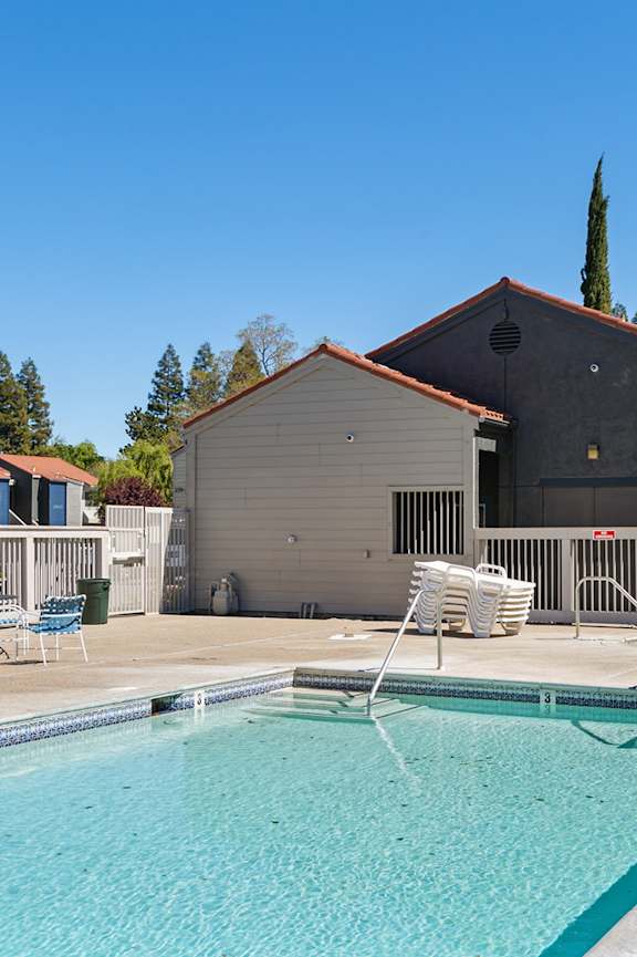 A small pool in a backyard with a house in the background.