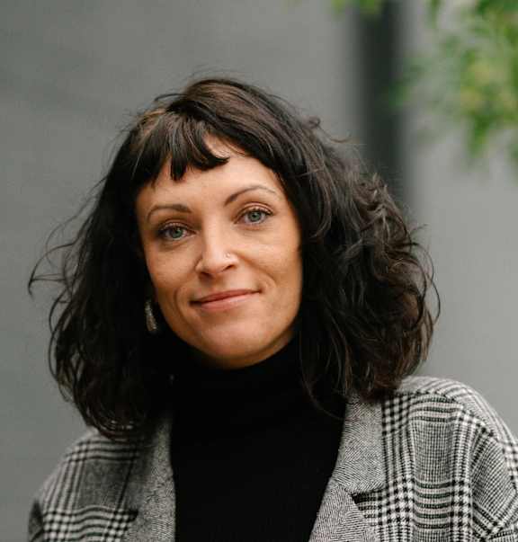 A woman with a black turtleneck and a plaid jacket.