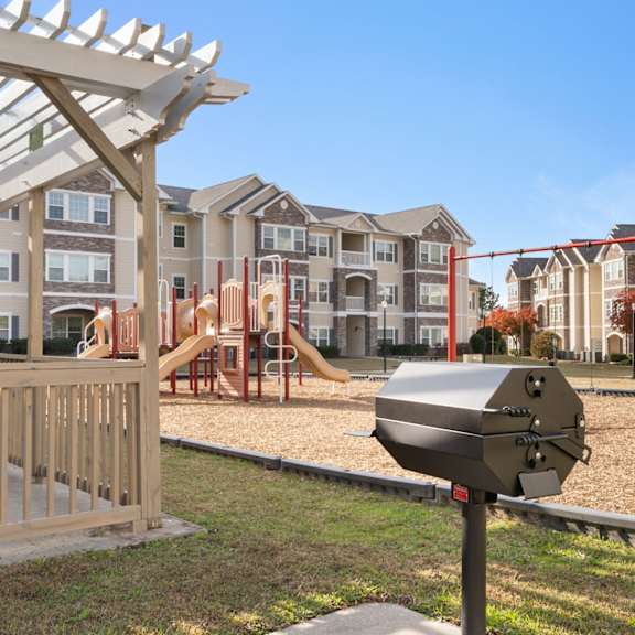A foosball table is in the middle of a room with a brick fireplace and a chandelier. at Stone Gate Apartments, Spring Lake, 28390