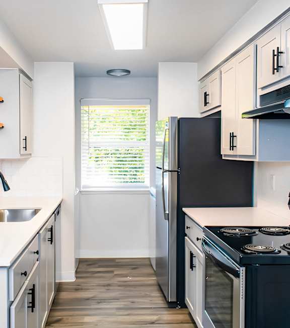 A kitchen with white cabinets and black appliances.