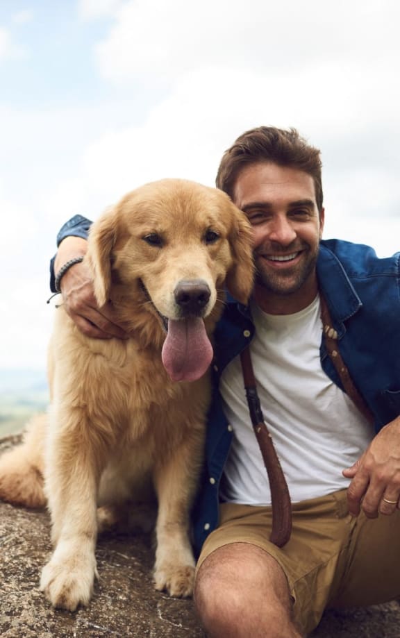 Man Smiling while Sitting on Rock with Dog