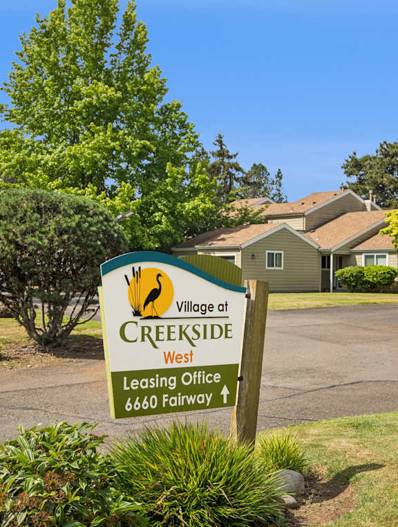 A sign for the Village at Creekside leasing office is in front of a building.