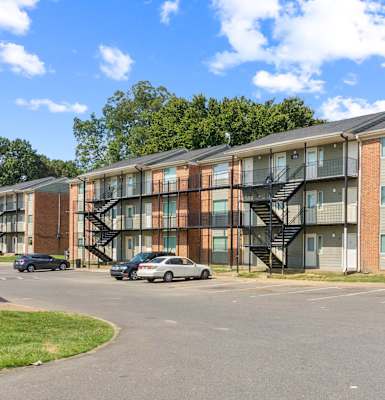 A large apartment complex with a parking lot in front.