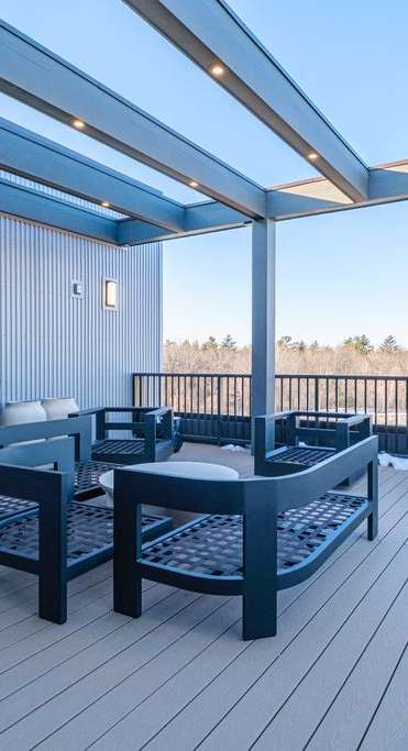 A wooden deck with a table and chairs under a roof.