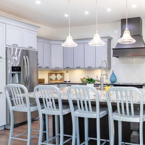 A kitchen with white cabinets and a blue vase on the counter.