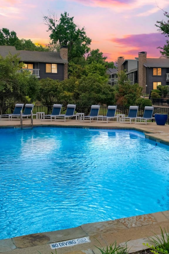 a swimming pool with orange chairs and a building in the background