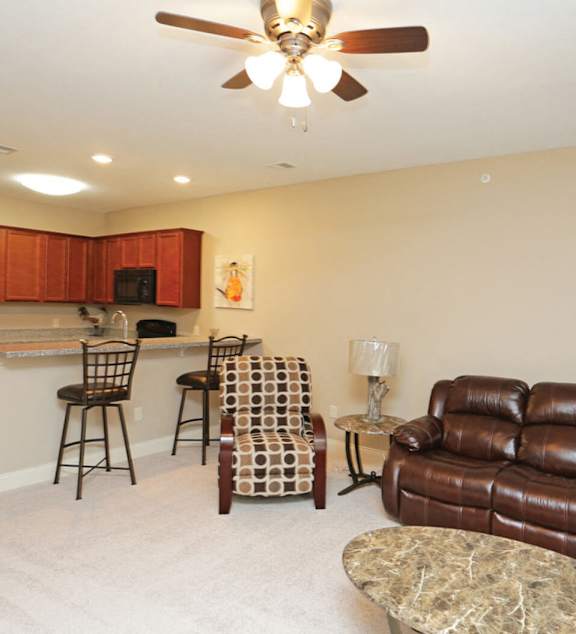 A living room with a brown leather couch and a kitchen area in the background.
