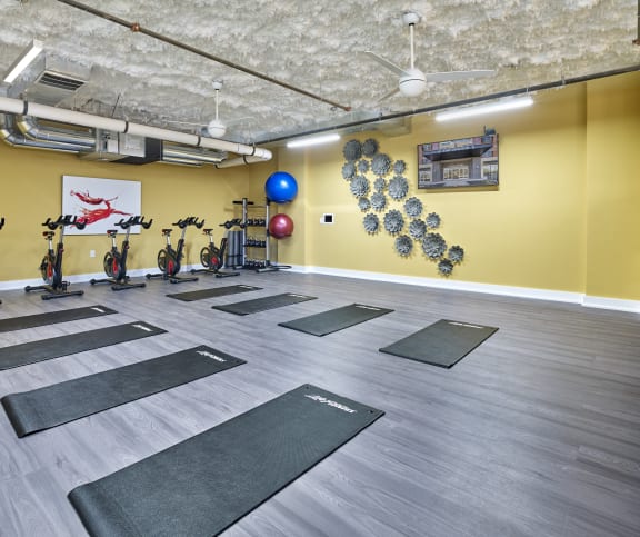 a yoga room with yoga mats on the floor and a yellow wall with bikes