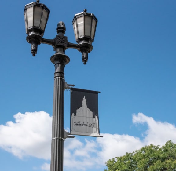 a lamp post with a flag on it and a blue sky with clouds in the background