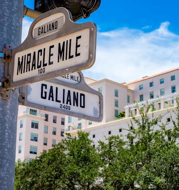 A street sign for Galiano and Miracle Mile stands in front of a building.