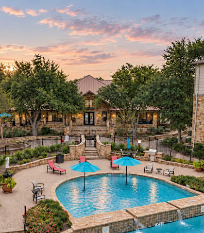 A large outdoor pool surrounded by a fence and trees.