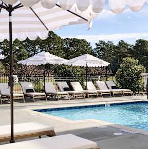 A pool area with sun umbrellas and lounge chairs.