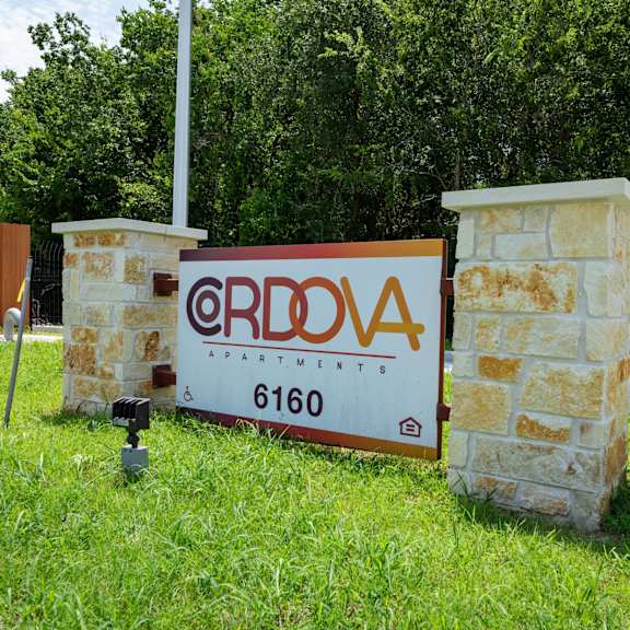 A sign for ERDOVA APARTMENTS stands in front of a stone pillar.