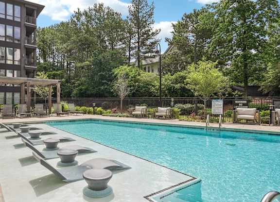 A large swimming pool with lounge chairs and cabana.