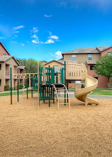 A basketball court with a bench on the side and two houses in the background.