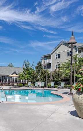 A large outdoor swimming pool surrounded by lounge chairs and umbrellas.