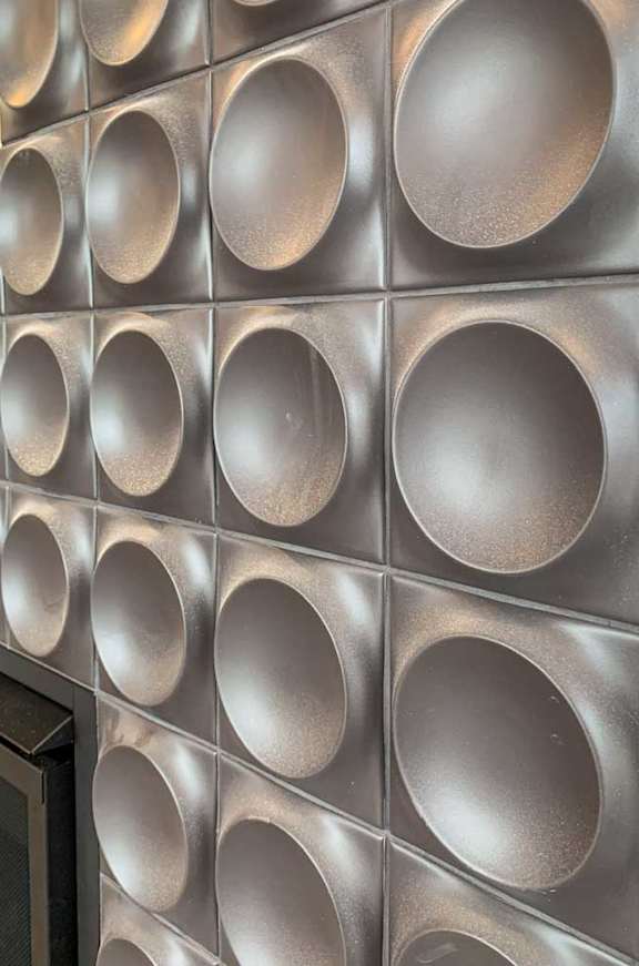 a fireplace accent wall with a series of circular tiles
