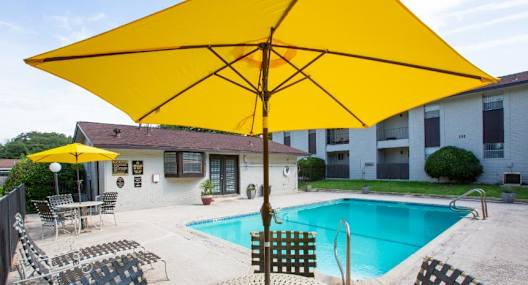 A yellow umbrella is over a table with chairs around it.