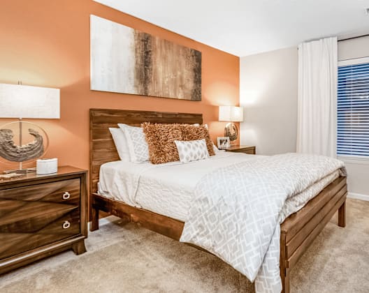 A bedroom with a bed, nightstand, and lamp.