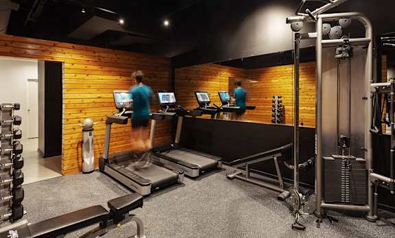 A gym with a brick wall and a person running on a treadmill.