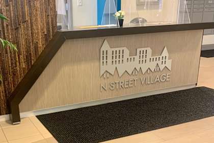 A wooden reception desk with a sign that says N Street Village.