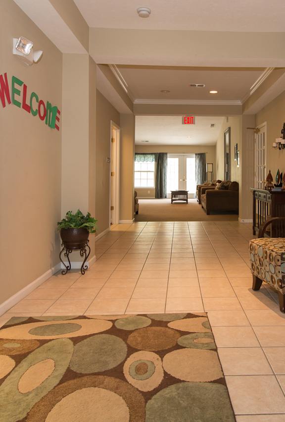 A hallway with a welcome sign and a chair with a pillow on it.