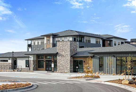 A modern building with a stone facade and a curved driveway in front.