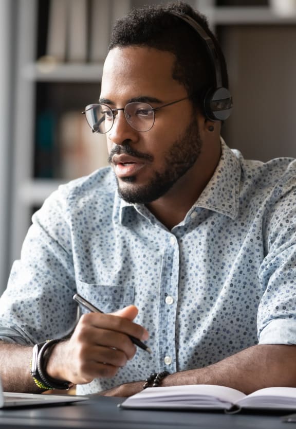 Man Sitting at Desk with Laptop and Headphones On