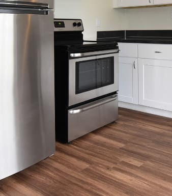 an empty kitchen with stainless steel appliances and white cabinets