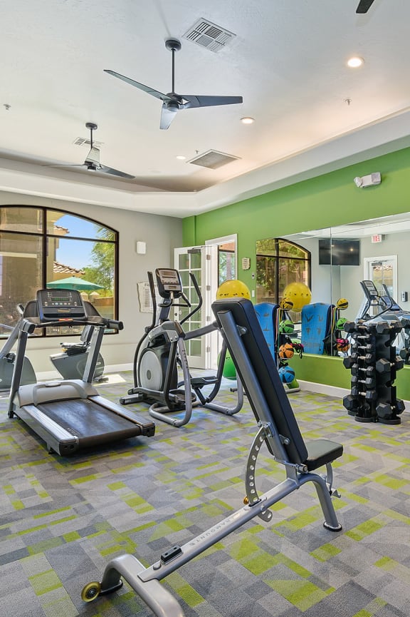 a gym with weights and cardio equipment and a green wall
