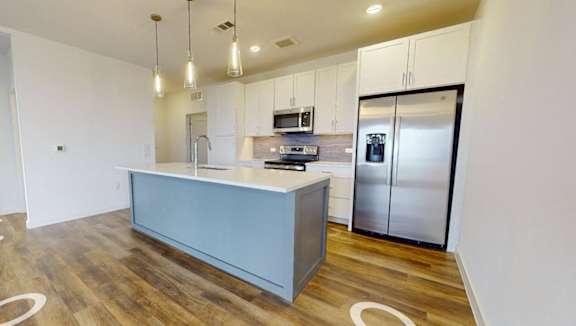 A kitchen with a wooden floor and a white wall.