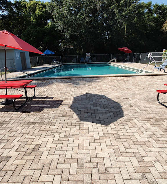 A patio with a table and chairs overlooking a pool.