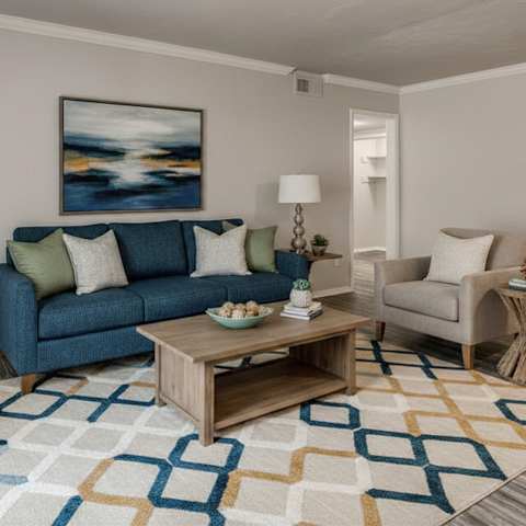A living room with a blue couch, a coffee table, and a painting on the wall.