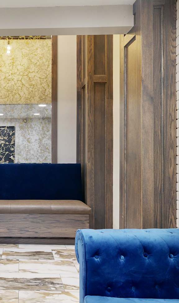 A blue velvet sofa sits in front of a wooden doorway.