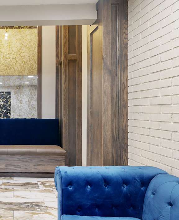 A blue velvet sofa sits in front of a wooden doorway.