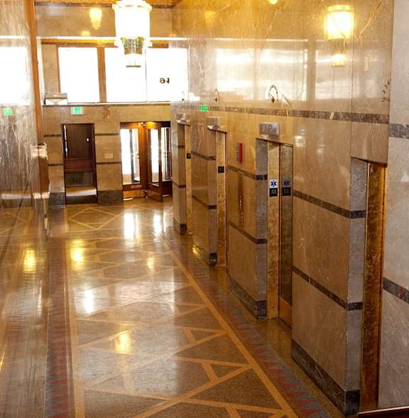 A hallway with marble floors and walls and a chandelier hanging from the ceiling.